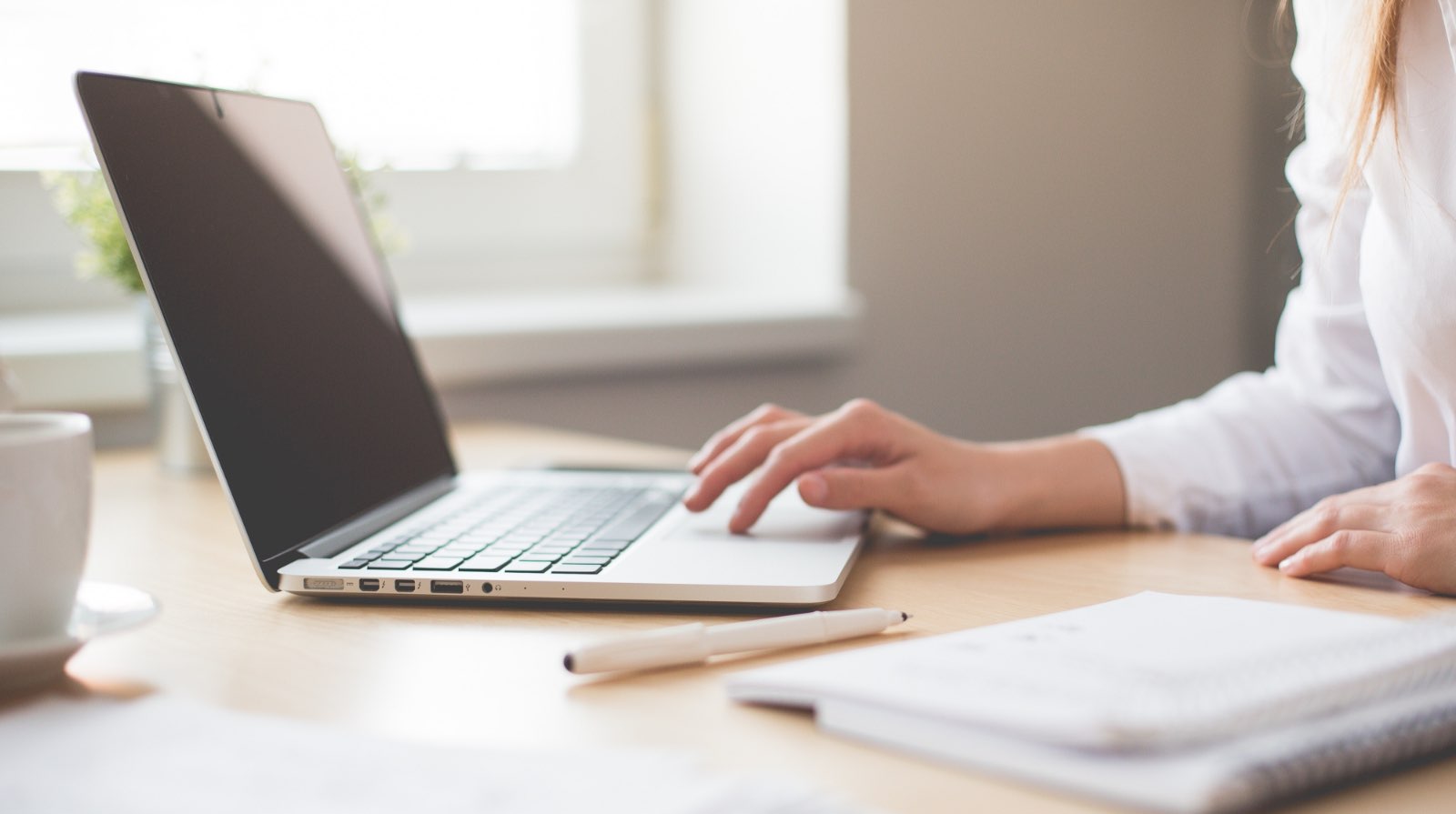 Photo of a laptop on a desk with someone making use of the track pad